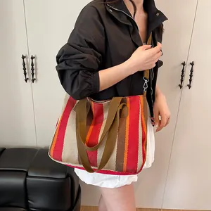 Close-up of striped canvas tote bag with brown woven handles and detachable shoulder strap