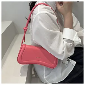 Pink PU leather underarm bag with knot strap detail and gold brand logo on model