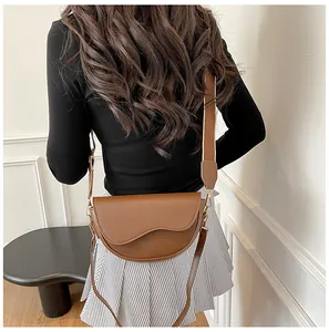 Détail d'un sac besace marron avec rabat ondulé et large bandoulière sur un modèle