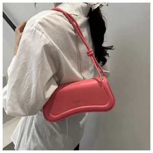 Detail of a pink curved hobo bag with XM & BAGS text and knotted shoulder strap