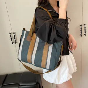 Close-up of striped canvas tote bag showing textured weave and leather straps details