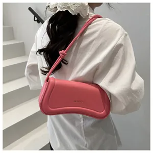 On-shoulder view of a bright pink leather underarm bag with a sleek curved silhouette