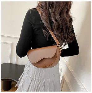 Détail du sac besace en cuir marron avec rabat festonné et logo embossé élégant