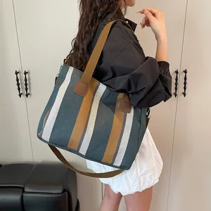 Striped canvas tote bag detail showing brown textile handle and reinforced base design