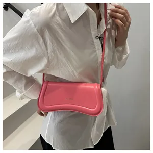 Close-up of pink curved faux leather shoulder bag with gold XM & BAGS logo detail