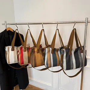 Detail of five striped canvas tote bags in various colors on a display rack