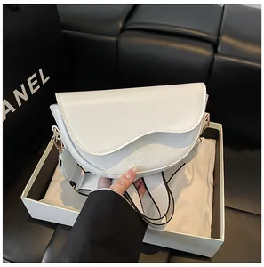 Détail du sac selle blanc avec bandoulière tissée et boucle dorée dans son emballage