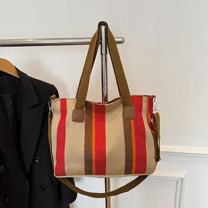Close-up of a striped canvas tote bag with brown straps and adjustable shoulder strap