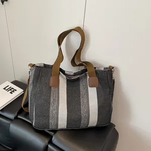 Detail showing high-quality striped canvas texture and leather accents on the tote bag