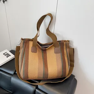 Detail view of large striped canvas tote bag with adjustable shoulder strap and silver buckles