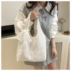 Détail d'un sac cabas en dentelle blanche avec broderies florales et un grand noeud