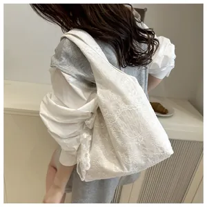 Vue de profil d'un sac cabas en dentelle blanche avec broderie florale et volants