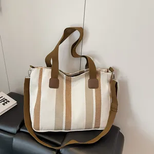 Detail of striped canvas tote bag with brown leather accents and adjustable shoulder strap