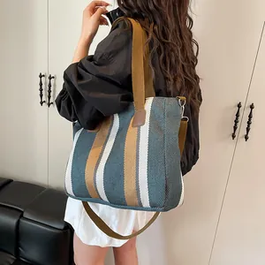 Striped canvas tote bag with brown shoulder strap for women shown in a lifestyle setting