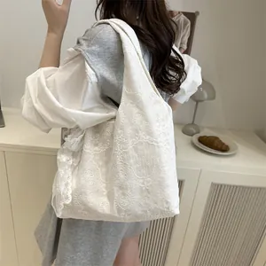 Sac cabas blanc avec broderie florale en dentelle porté par un mannequin en intérieur