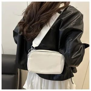 Detailed side view of white rectangular crossbody camera bag with wide fabric strap