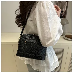 Detail of black woven texture shell crossbody bag with golden zipper and strap