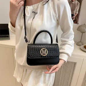 Modische schwarze Handtasche mit Webstruktur und goldener M-Schnalle auf modernem Dekor