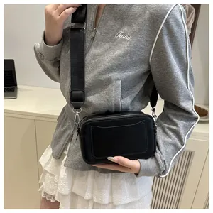 Detail of black rectangular camera bag with dual zippers and wide shoulder strap