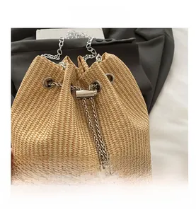 Detail of straw bucket bag with silver chain strap and pearl drawstring closure