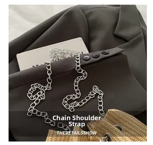 Detail showing the silver metal chain shoulder strap on a straw bucket bag