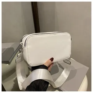 Close-up of a white camera bag featuring dual zippers and a wide nylon shoulder strap