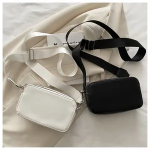 Flat lay of minimalist black and white crossbody camera bags with wide nylon straps