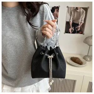 Detailed shot of black bucket bag with silver chain and white pearl drawstring charms