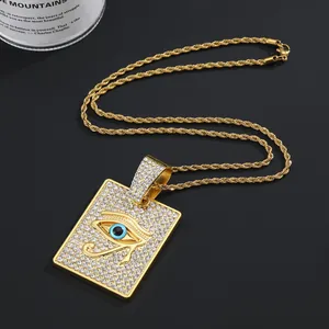 Détail du pendentif hip hop serti de cristaux et œil d'Horus sur une chaîne torsadée dorée