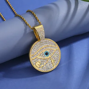 Detail of gold Eye of Horus pendant with iced-out rhinestones and a blue eye center