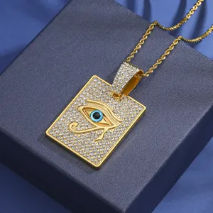 Vue détaillée du pendentif carré doré Oeil de Horus serti de cristaux sur boîte