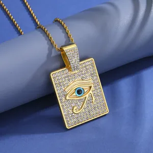 Détail macro du pendentif Œil d'Horus doré pavé de strass sur une chaîne de torsion