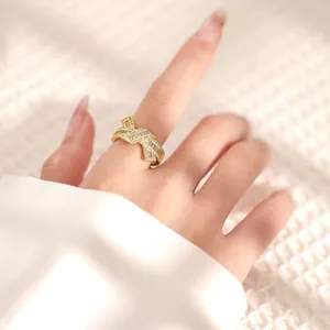 Close-up of elegant gold bow ring with sparkling zircons worn on finger