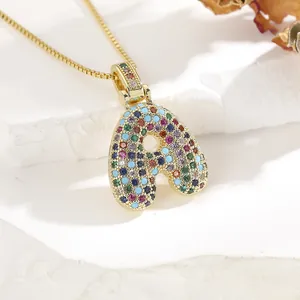Macro shot of gold letter A pendant with colorful pavé cubic zirconia on box chain