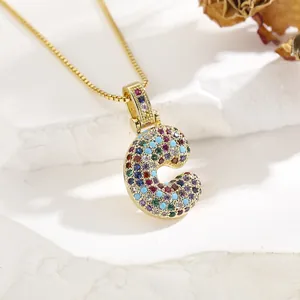 Macro shot of gold-plated letter C pendant necklace with colorful micro-inlaid gemstones