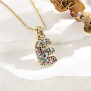 Detail of gold box chain with multi-color cubic zirconia paved letter E pendant