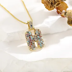 Detailed close-up of letter H pendant with multicolored zircons on a gold-tone chain