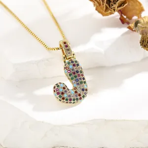 Macro shot of letter J pendant featuring multi-colored cubic zirconia on a gold chain