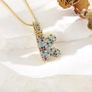 Macro view of gold letter K pendant necklace with colorful cubic zirconia inlay