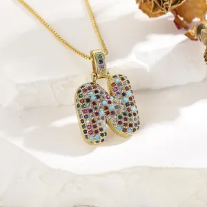 Macro view of bubble letter N pendant with colorful pavé cubic zirconia on gold chain