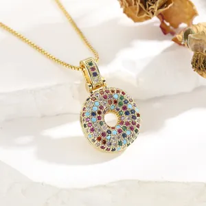 Detail of gold-plated pendant necklace featuring colorful zircon stones on white rock