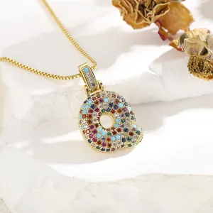 Detailed macro view of gold letter Q pendant inlaid with colorful zircon stones on box chain