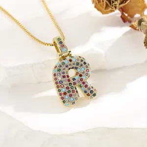 Close-up of golden letter R pendant with multi-color zircon stones on a box chain