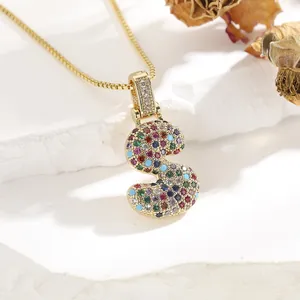 Detailed close-up of a golden S-letter pendant featuring vibrant multi-color zircon stones
