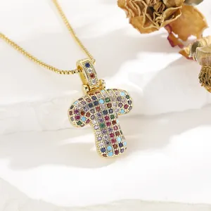 Detailed close-up of a golden letter T pendant necklace with colorful micro-inlaid zircons