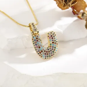 Detail of gold letter U pendant necklace with colorful micro-set cubic zirconia stones