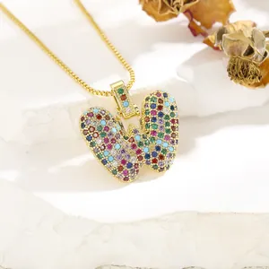 Detail of gold-plated necklace with a colorful zircon-encrusted letter W pendant