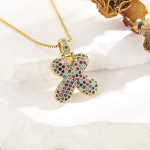Macro shot of gold letter X pendant with colorful cubic zirconia and stone base