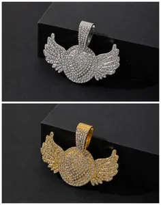 Detalle de colgantes de alas plateados y dorados con circonitas estilo hip hop iced out