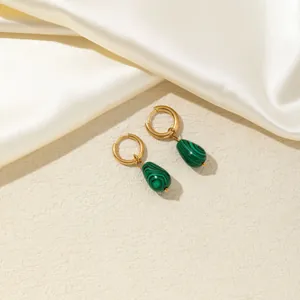 Dettaglio dei orecchini in malachite a goccia con cerchi dorati lucidi su seta beige